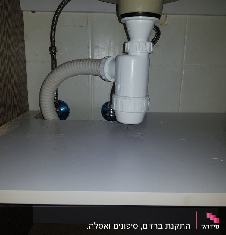 צינור ניקוז לבן מתחת לכיור במטבח